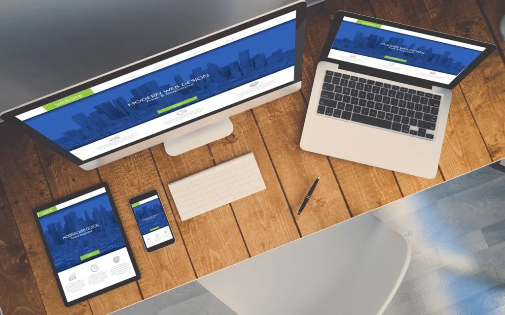 Workspace with computer, laptop, smartphone, and stationery on wooden desk.