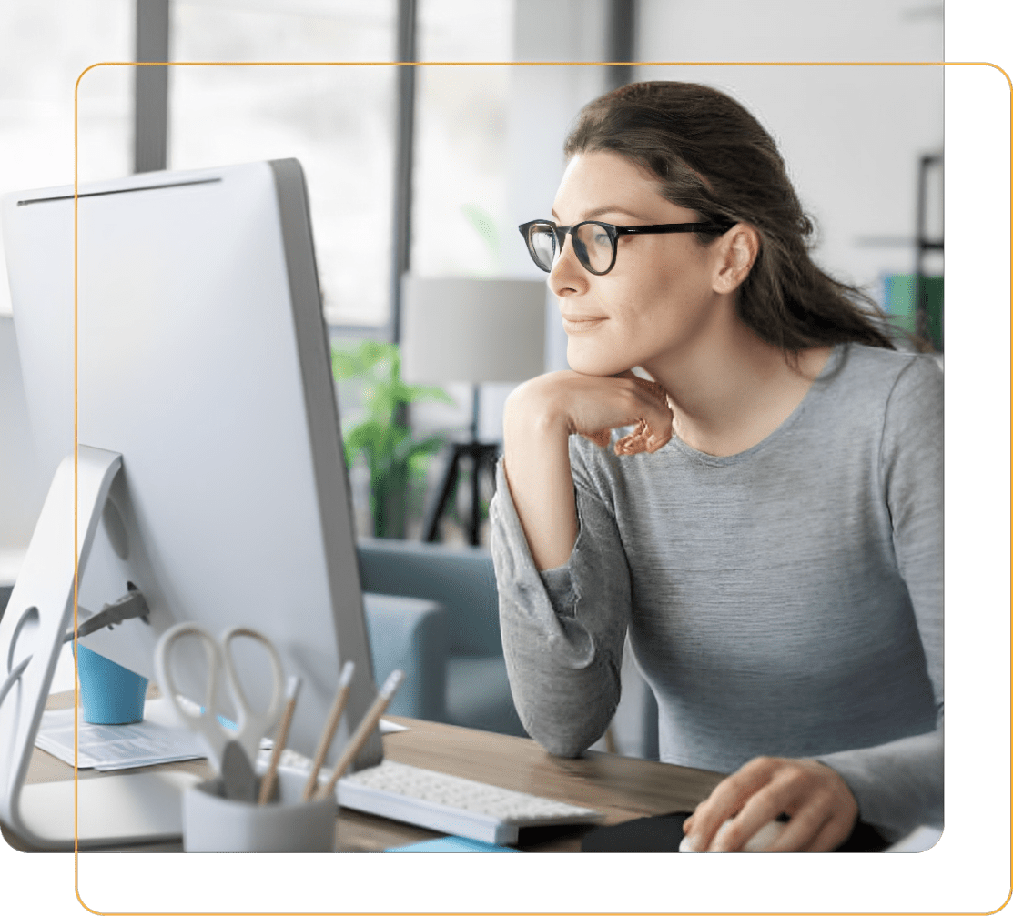 A woman with glasses working on a desktop computer. A woman with glasses working on a desktop computer.