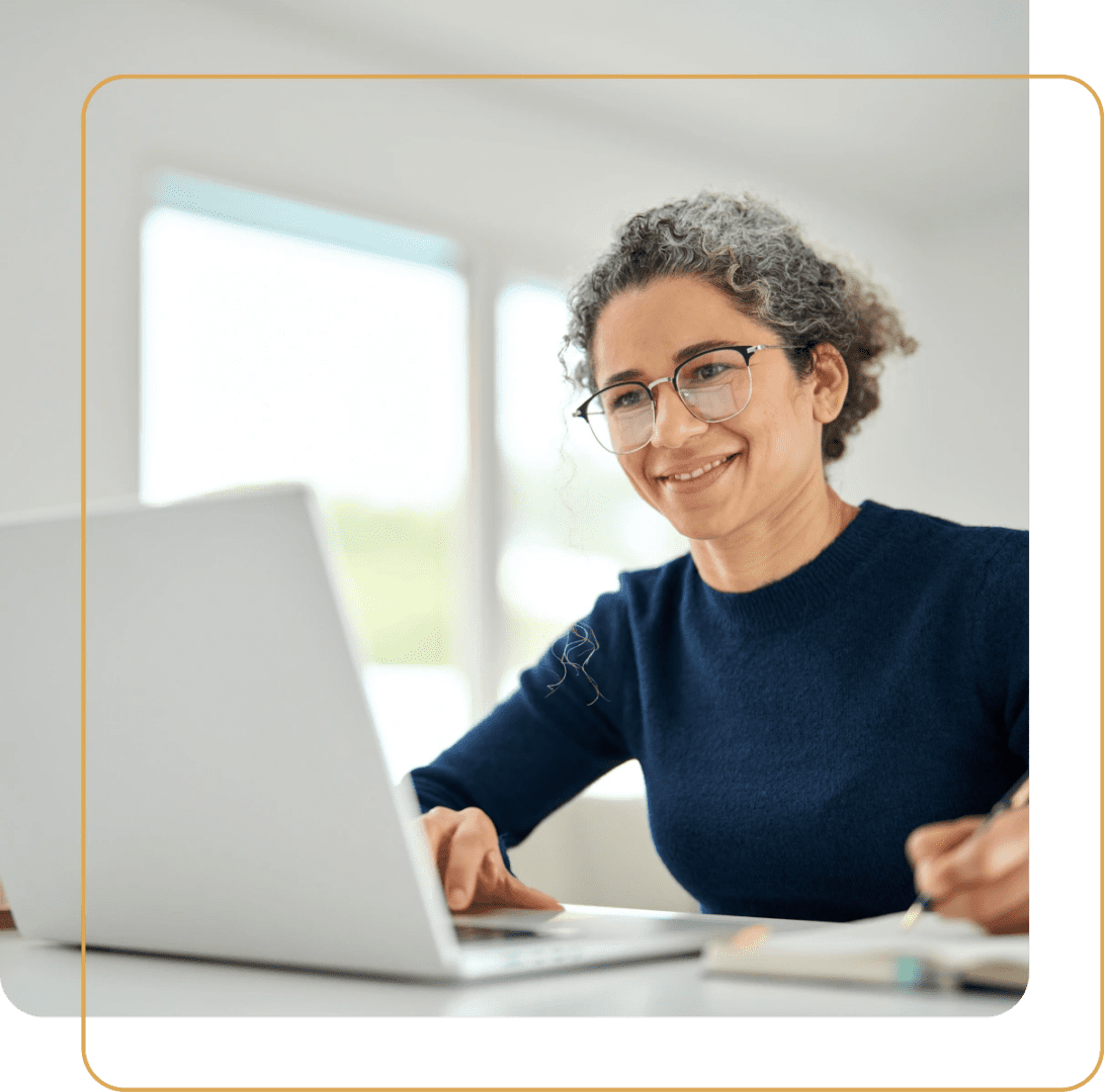 A woman working on a laptop with a thoughtful expression.