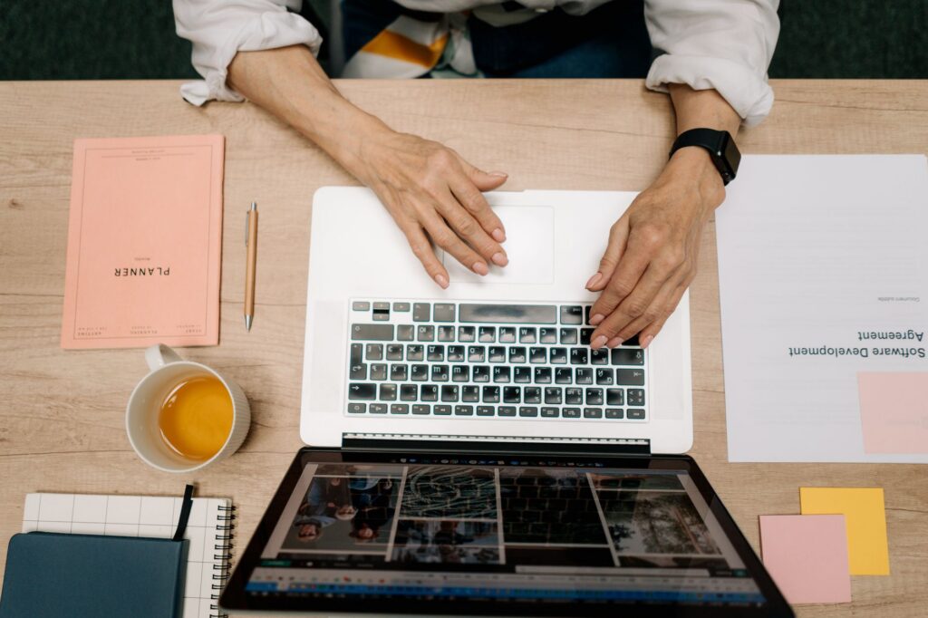 Hands using laptop with planner and tea