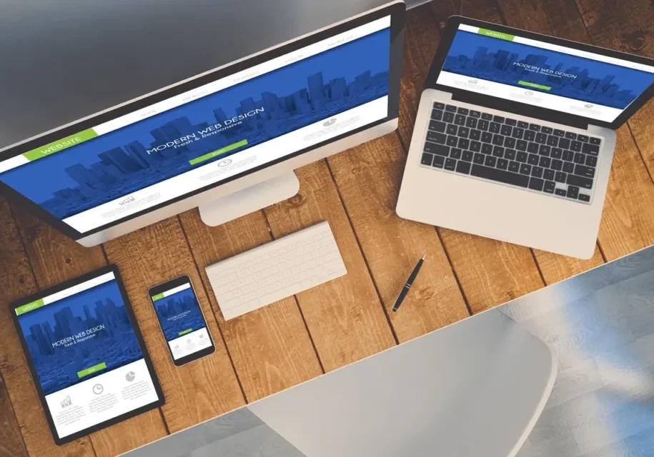 Workspace with computer, laptop, smartphone, and stationery on wooden desk.