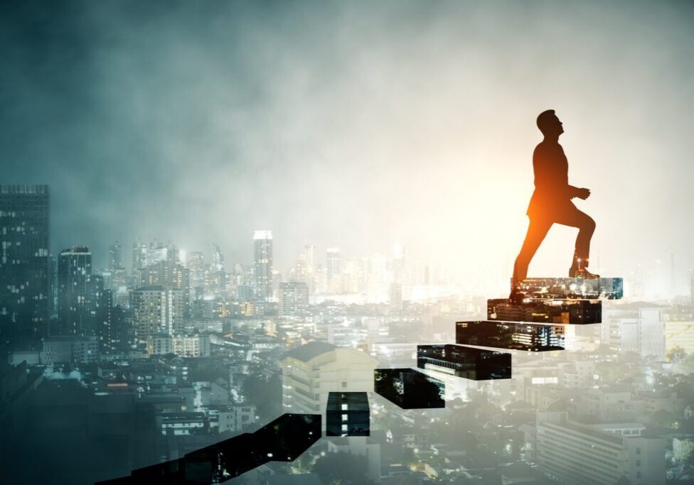 Silhouette of a person climbing rising steps made of city buildings against a glowing skyline