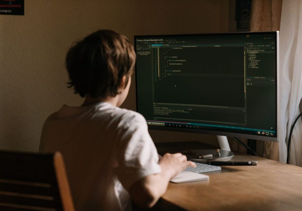 Person coding at desktop with large monitor