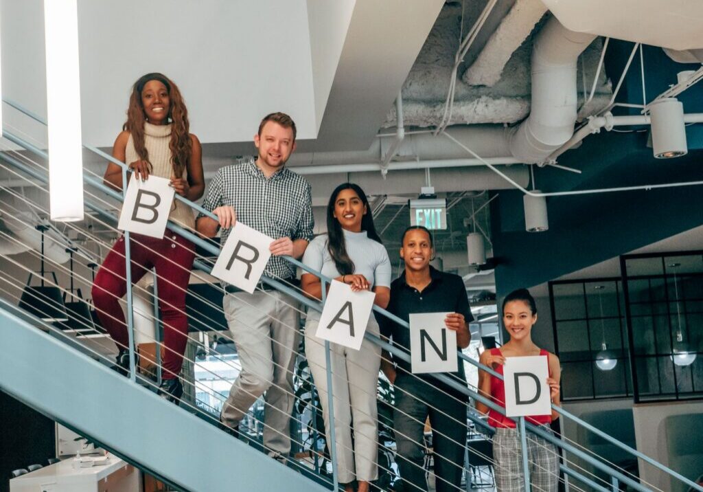 Team on stairs holding brand letter signs
