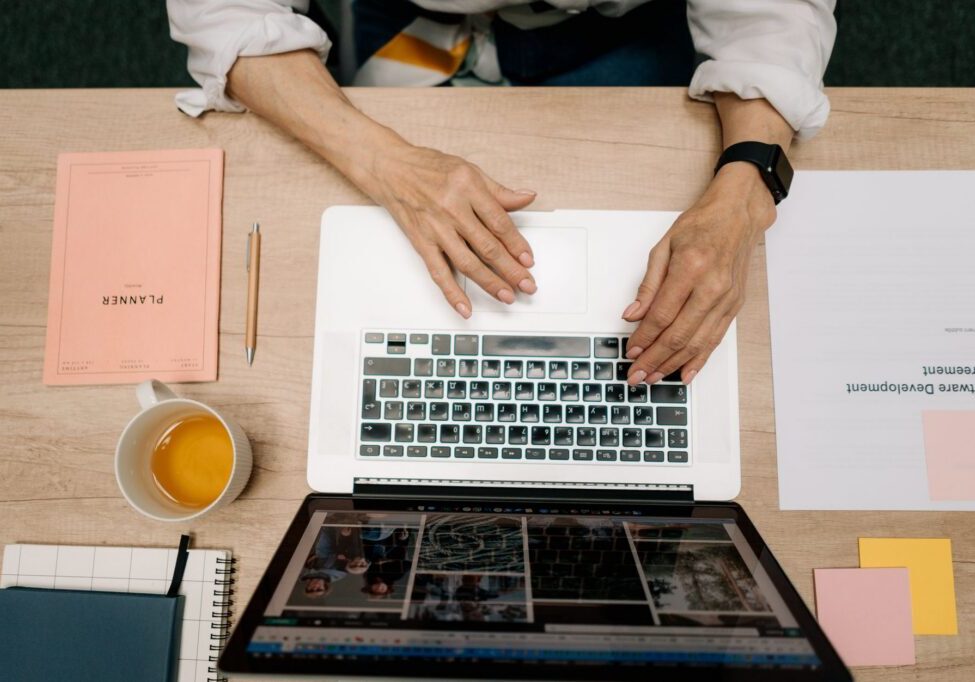 Hands using laptop with planner and tea